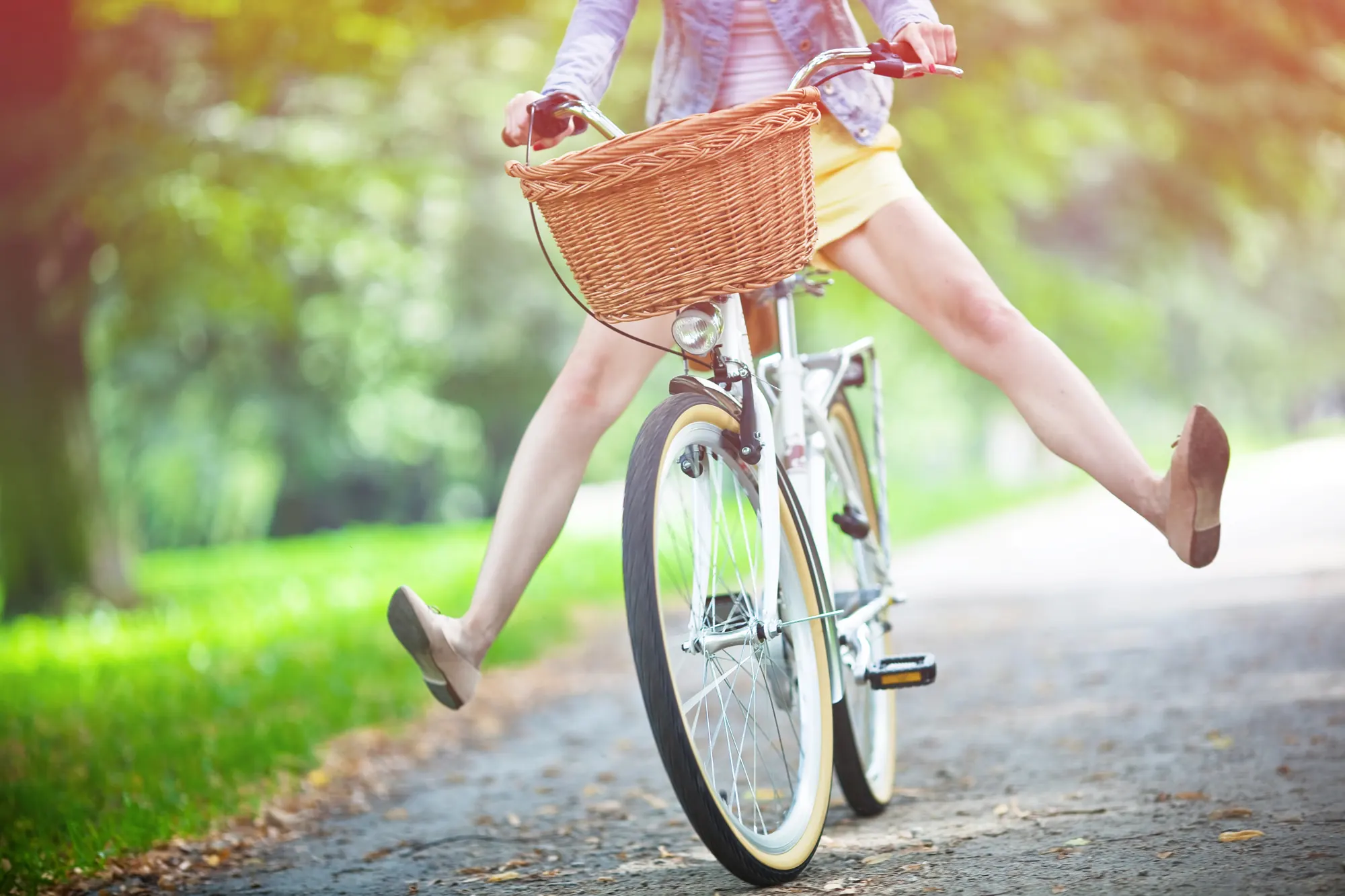 Une femme fait du vélo dans une allée arborée, les jambes écartées